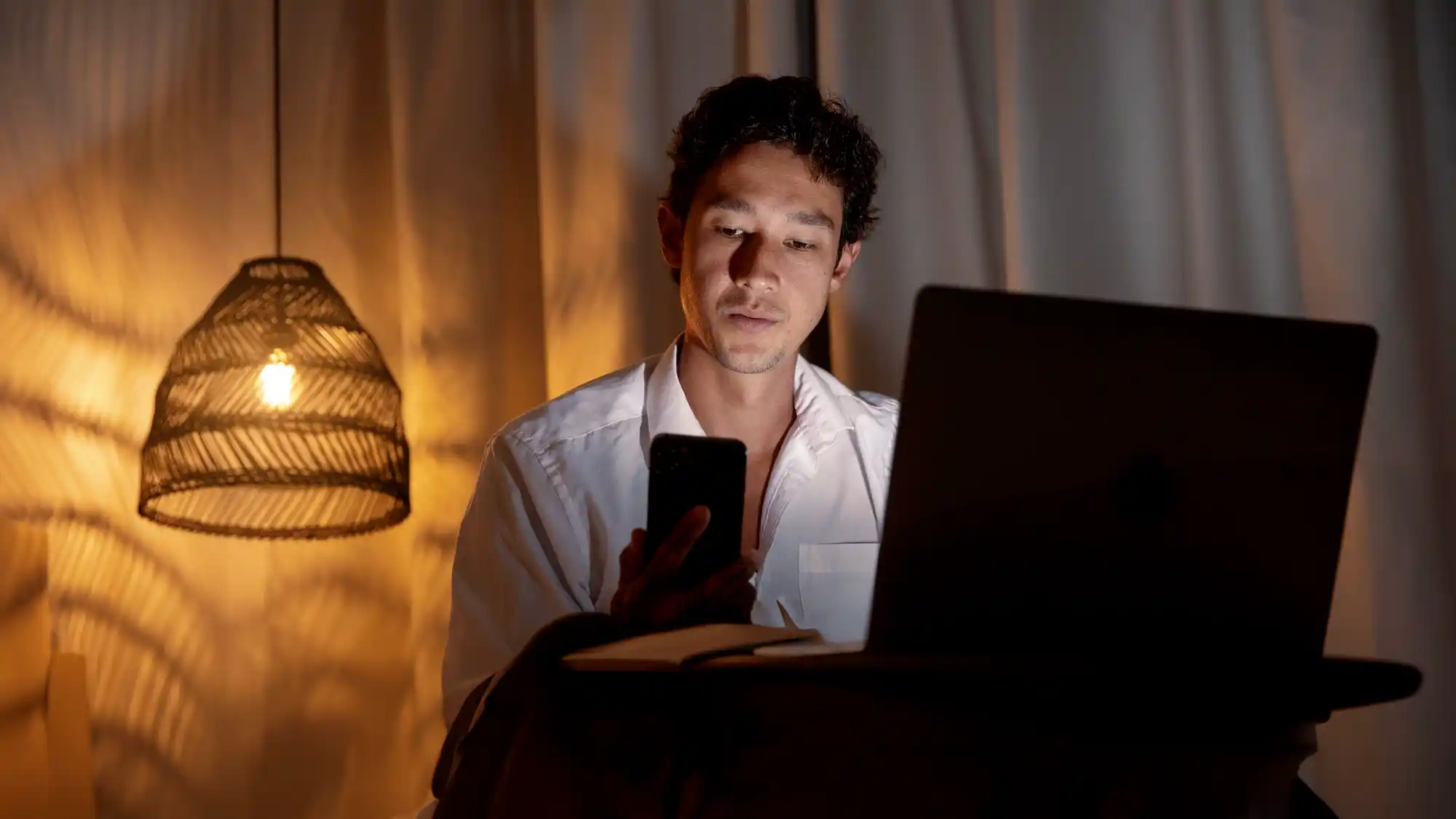 homeowner at home looking at his bill on the phone in evening warm light ambience