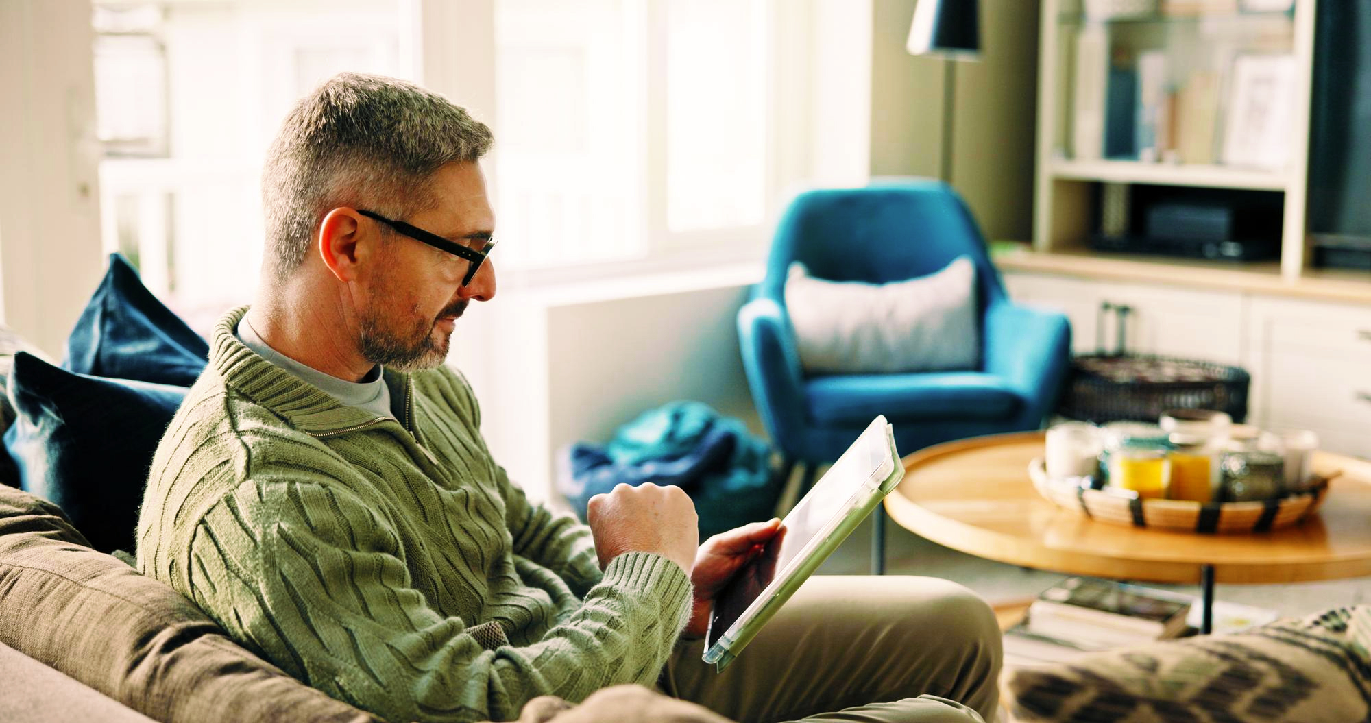 homeowner sitting in living room and looking at his electric bill copy